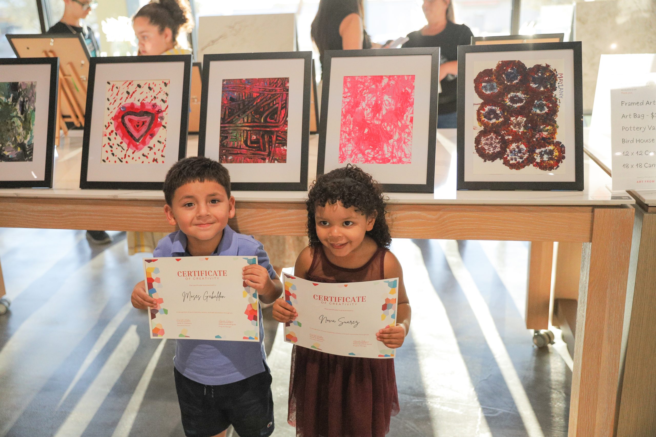 art-from-the-heart-artwork.png Children proudly displaying certificates of creativity at a Variety of the Desert art showcase.